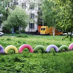 Kolorowe opony do ogrodu, pomalowane na różowo, fioletowo, żółto i zielono, tworzą radosną ozdobę.