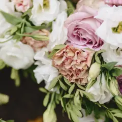 Delikatny eustoma bukiet z różowymi i białymi kwiatami, ozdobiony zielonymi liśćmi.