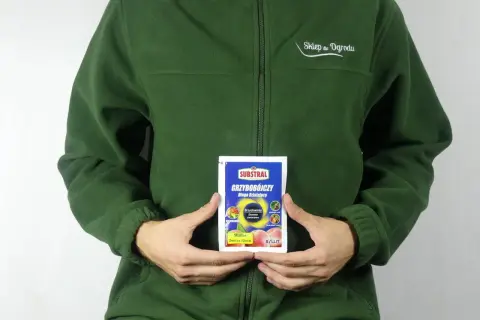 Osoba w zielonej bluzie trzyma opakowanie środka grzybobójczego SYLLIT. Preparat przeznaczony jest do ochrony drzew owocowych.