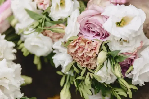 Delikatny eustoma bukiet z różowymi i białymi kwiatami, ozdobiony zielonymi liśćmi.