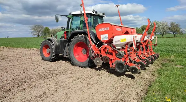 Zielony traktor z siewnikiem Gaspardo na polu. Idealny czas, by zasiać kukurydzę i cieszyć się plonami.