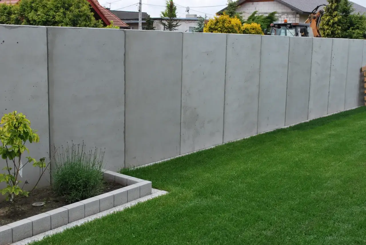 Nowy, wysoki płot z płyt betonowych, który zapewnia prywatność. Szybki beton to idealne rozwiązanie dla nowoczesnych ogrodzeń.